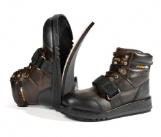 A pair of rugged brown and black boots with straps and metal eyelets, featuring a high top design and a sturdy sole.
