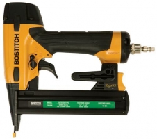 A Bostitch pneumatic nail gun with a yellow and black design, featuring a magazine for nails and a connector for air supply.