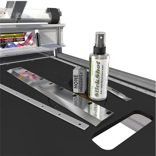 A close-up view of a work surface featuring a lubricant spray bottle labeled 'Slick Shot' alongside metal strips and a ruler, with a focus on maintenance tools.